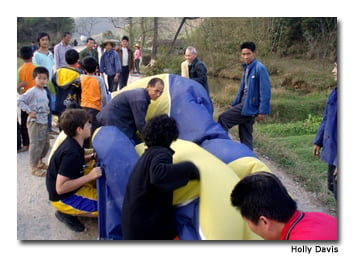 The collaborative efforts of villagers and schoolchildren make folding up the balloon a manageable task.