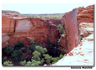 Kings Canyon was formed in layers by the red sand of the desert. The Garden of Eden, a watering hole and refuge for ancient plants, feeds the waterfall coming out of the rift between the cliffs.