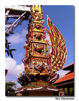 The intricately painted funeral tower is decorated with numerous colored masks.