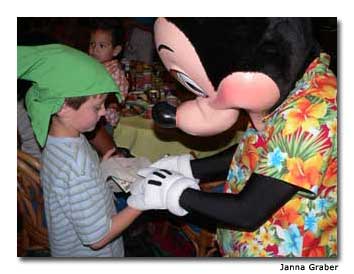 Mickey Mouse signs his autograph for an adoring young fan.