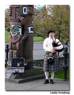 A Scottish bagpiper and a First Nations totem pole on the harbor walk signify Victoria’s historical cultural influences.
