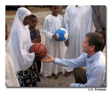 Mark Green hands a basketball to one of the orphans of Misugusugu village in Kibaha in the orphanage of the Mwinyibaraka Center.