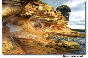 tasmania Butterscotch-colored cliffs backlit by a stormy sky on Maria’s western shoreline in Tasmania.