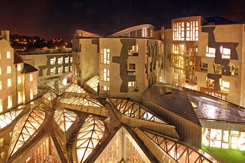 The Scottish Parliament lit up at night, as seen from above. 