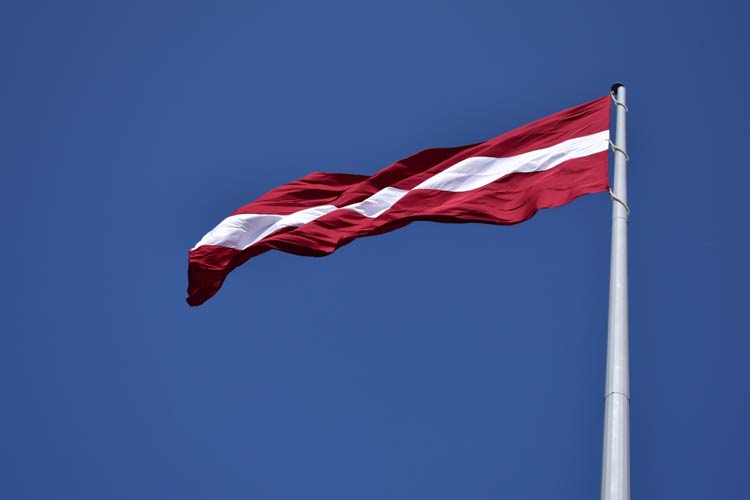The Latvian flag flies in a summer breeze.