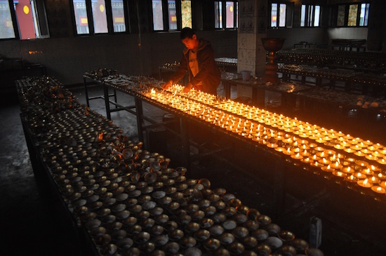 A Buddhist monk lights butter lamps in Sherabling Monastery, Himachal Pradesh. Lighting of butter lamps in Buddhist monasteries is a ritual, performed with divine incantations.