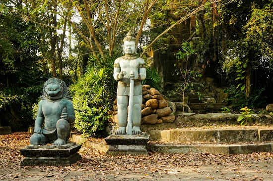 Two carved statues are nestled in the forest.