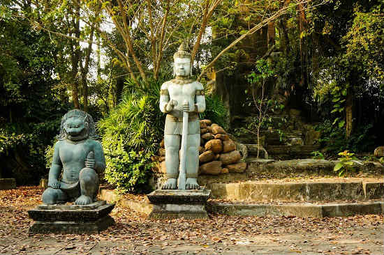 Two carved statues are nestled in the forest. 