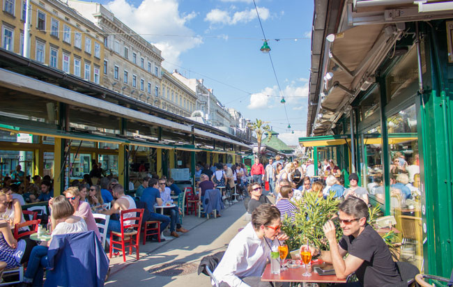 Diners enjoy the sun at one of the restaurants at the Naschmarkt in Vienna. Photo by Janna Graber