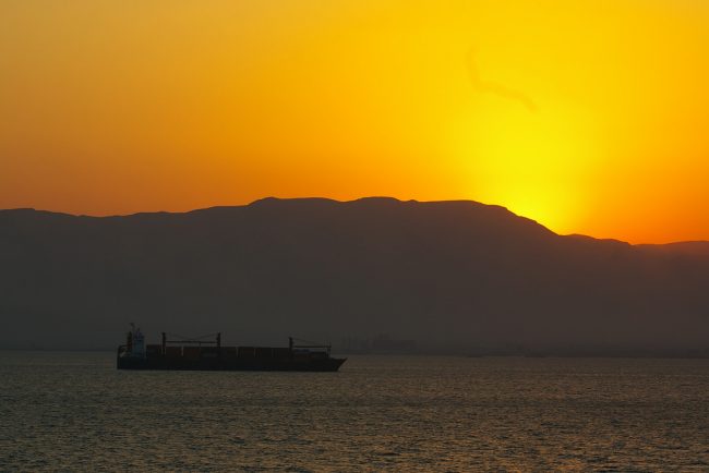 A container ship moves along the Suez Canal at sunset. Flickr/Tim