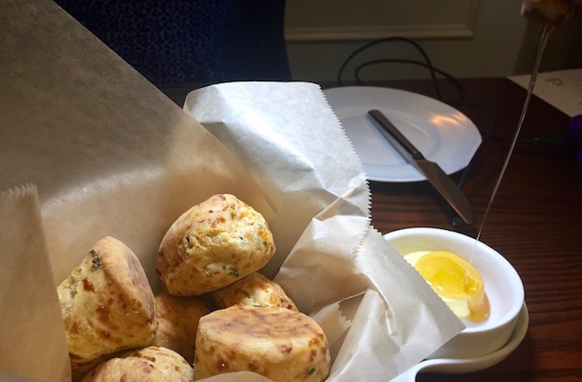 Carolina Biscuit with Asiago Cheese and Caramelized Onions. Honey is drizzled onto butter. Photo by Claudia Carbone