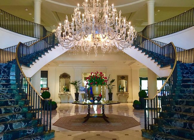 Classic Southern "Open Arm" staircase showcases crystal chandelier in the marble lobby. Photo by Claudia Carbone
