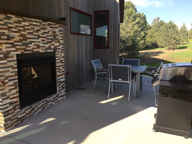 Wrap-around patio features a fireplace, furniture and grill. Photo by Claudia Carbone