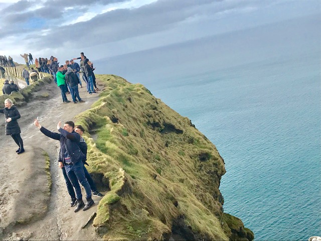 Tourists take selfies along Cliffs of Moher.