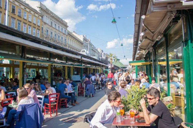Diners enjoy the sun at one of the restaurants at the Naschmarkt in Vienna