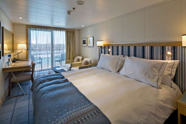 Deluxe Veranda cabins on Viking Ocean ships feature comfy king beds, a sitting area and desk.