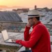 Digital nomad sitting outdoors on the beach with a laptop, Pinterest. Photo by Oscar Gutierrez Zozulia, iStock