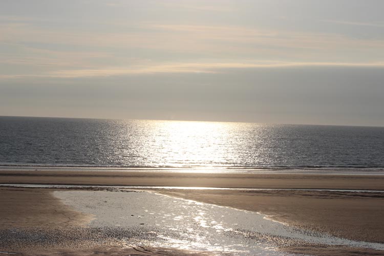 The sun beginning to set over a silvery sea in Jersey in the Channel Islands.