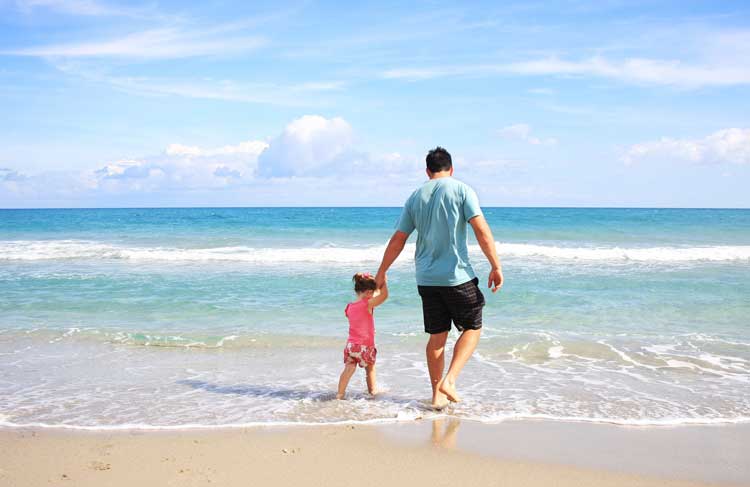Man walking with his child on the beach.