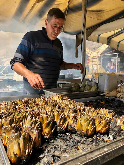 The vendor gave each prickly artichoke a generous slathering of olive oil and finely chopped parsley