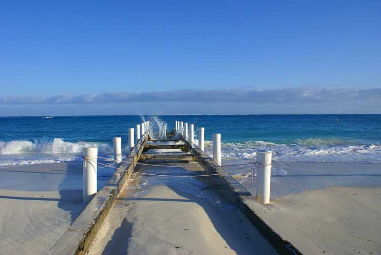 Waves crashing against the jetty on a sunny beach walk.