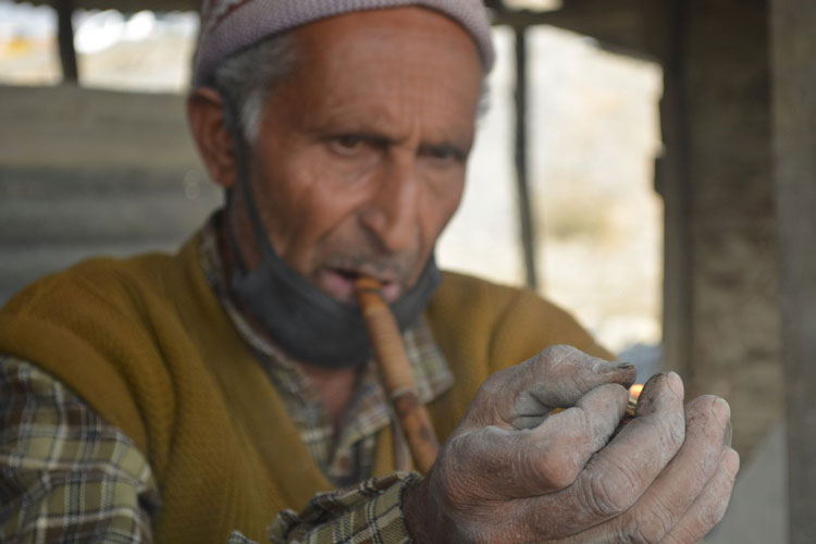 Endless toil on stone has wrinkled the man's hands, but his grip remains solid.