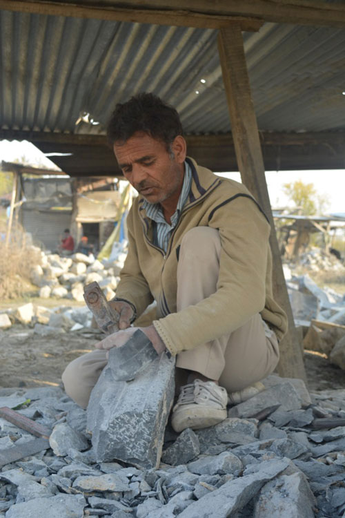 Ali Mohammad at work carving on a pile of stones.