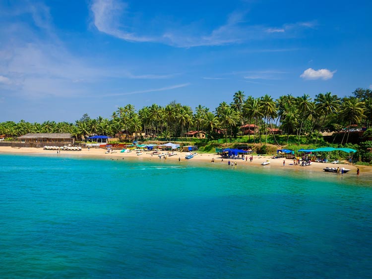 Tourists soak up the sun along the bright beach in Goa, India.