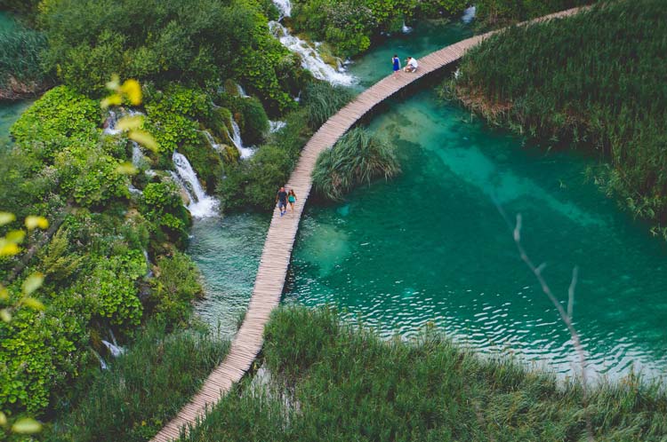 Travelers exploring the plants and waterfalls in Plitvice Lakes National Park.