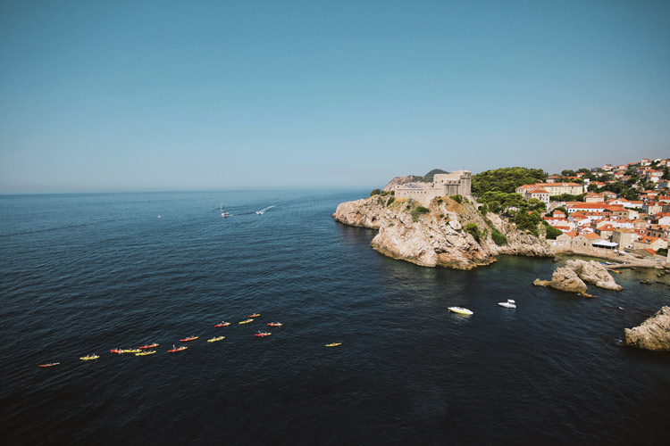 Kayaking group paddles back to campgrounds on shore in Dubrovnik, Croatia.