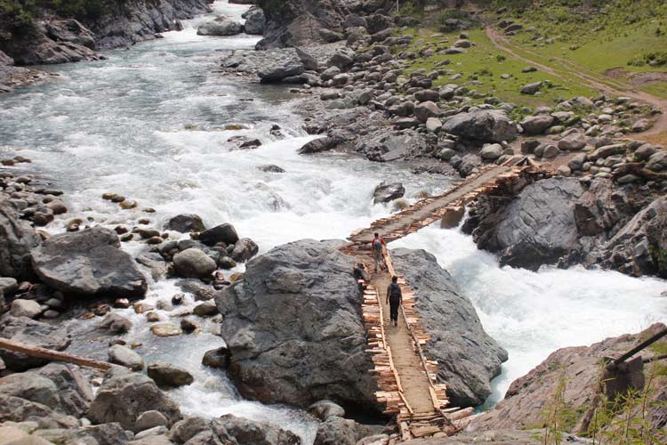 Hikers cross a makeshift log bridge over a stream in Kongwattan area of Kulgam district of south Kashmir region. This trail leads to Kounsarnag alpine lake in the Pir Panjal mountain range in Kashmir.