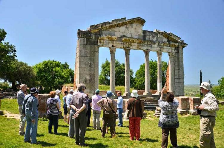 Tourists admiring the ancient ruins of Apollonia city at Archaeological Park.