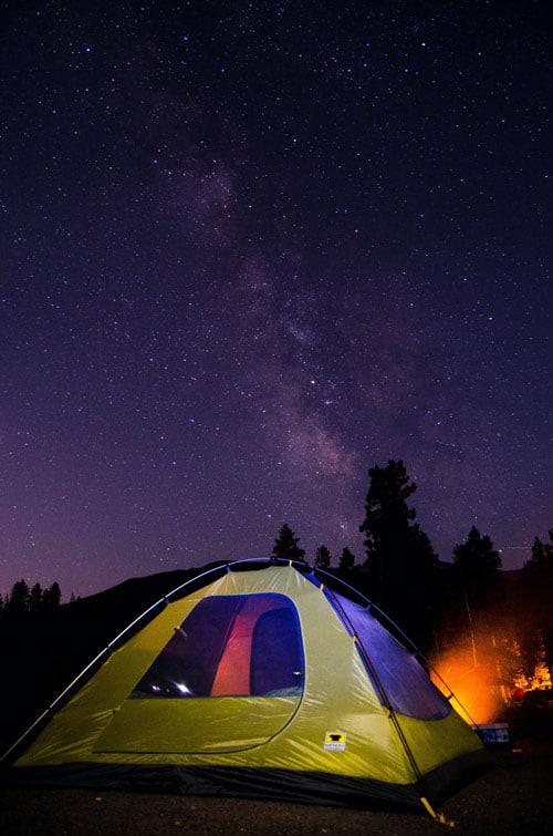 Tent illuminated underneath the night's star speckled sky