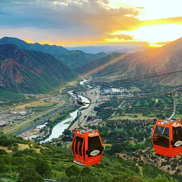 Gondolas with a sunset and mountainside backdrop