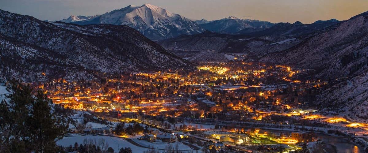 Picture of Glenwood Springs city lights nestled in between snowy mountain hills