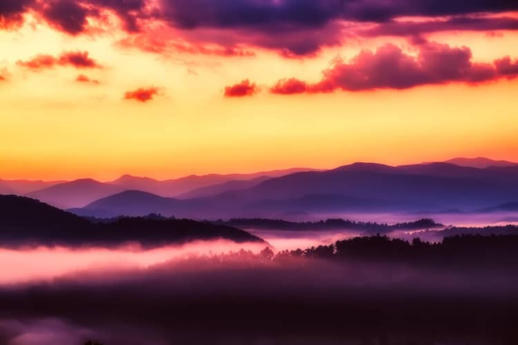 Shadowed and smoky mountain view with a fiery sky above