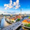 Berlin's iconic TV Tower dominates the skyline above the Spree River and the city's colorful rooftops. Image by SeanPavonePhoto from Getty Images Pro via Canva