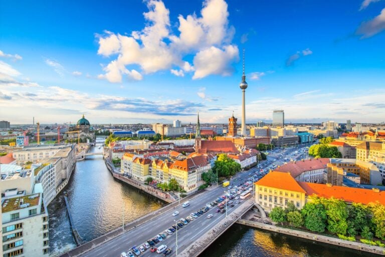 Berlin's iconic TV Tower dominates the skyline above the Spree River and the city's colorful rooftops. Image by SeanPavonePhoto from Getty Images Pro via Canva