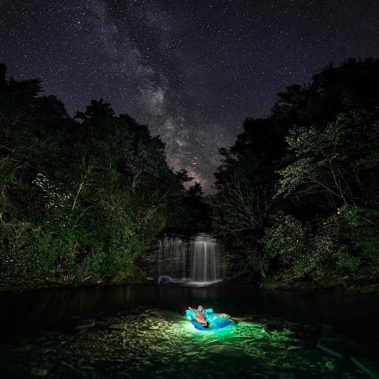 Astrotourism leads some travelers to a floating raft in front of a waterfall in North Carolina, where the Milky Way can be seen away from the city lights. Photo by Tom Moors Photography