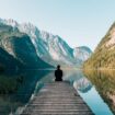 Contemplative person sitting at edge of mountain lake. Photo by Simon Migaj