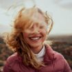 Female solo traveler smiles on a mountain. Photo by iStock