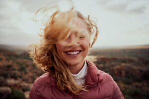 Female solo traveler smiles on a mountain. Photo by iStock