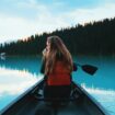 Woman paddling in a canoe by Roberto Nickson