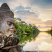 Stone face Asura on causeway near South Gate of Angkor Thom in Siem Reap, Cambodia. Photo by iStock