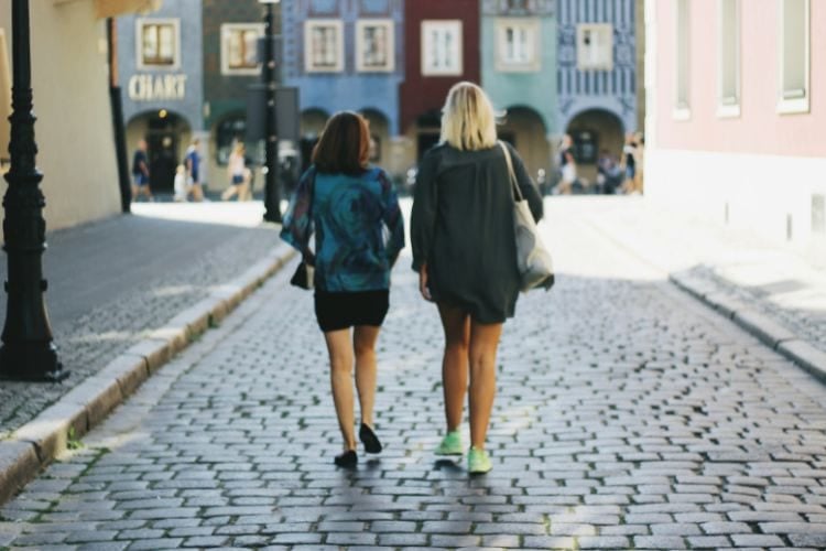 two people walking on cobblestone street