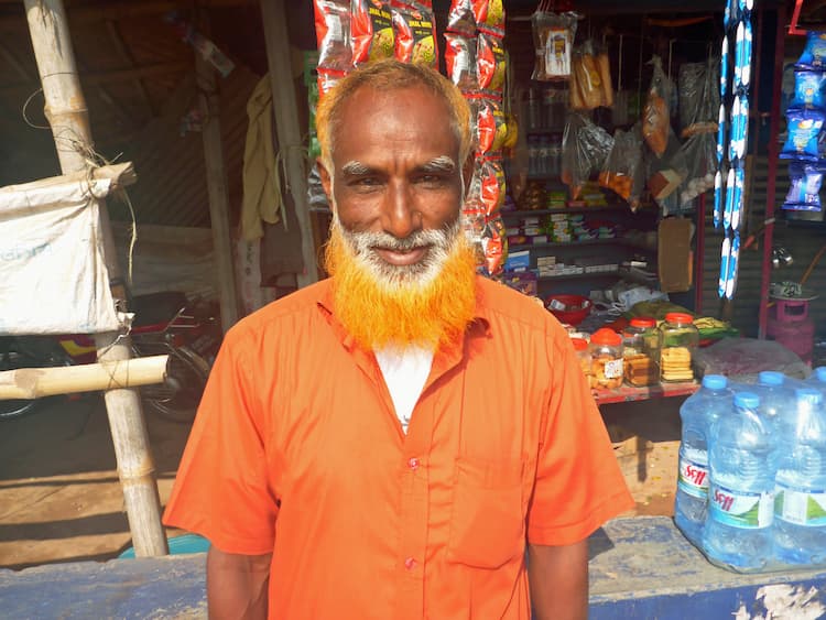 Man with an orange beard happily standing for a portrait in town of Rajshahi. Photo by Edward Placidi