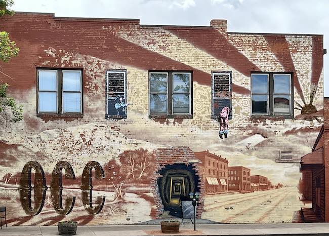 Mural on a building depicting the tunnels and a man escaping from a bordello on the wet side. You can see the dry side building in the painting. Photo by Claudia Carbone