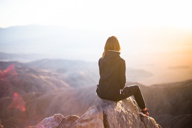 Women sitting on a mountaintop. Photo by Denys Nevozhai, Unsplash