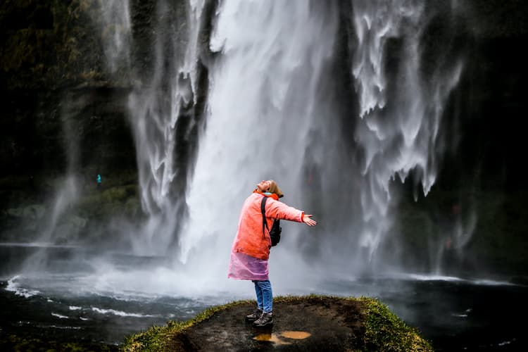 Traveler under a waterfall. Photo by Daria Gordova, Unsplash