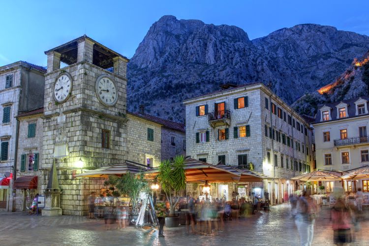  Scene in the medieval town of Kotor, Montenegro at twilight, featuring the Square of Arm and the clock tower near the Maritime entrance gate